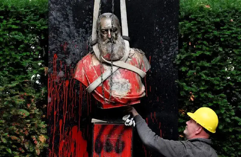 An employee helps to remove the vandalized statue of King Leopold II of Belgium